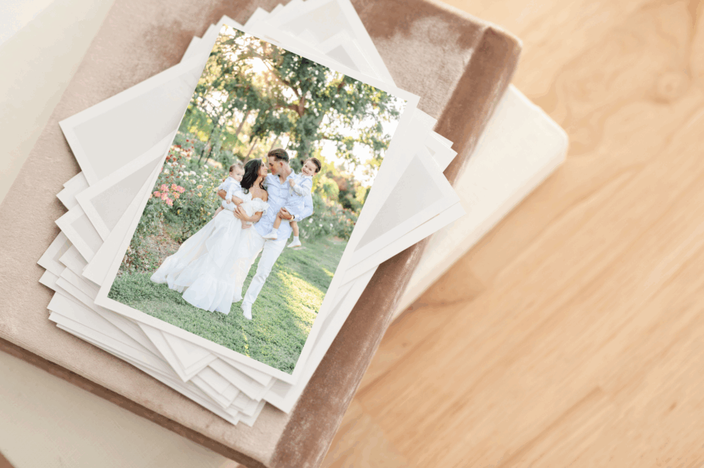 Fine art print stack of a young family in a blooming garden, styled on velvet heirloom albums with wood grain background.